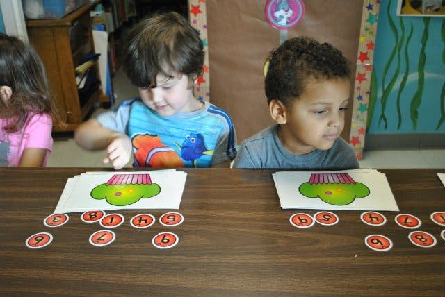 Two children at a table with number cards and cupcake images