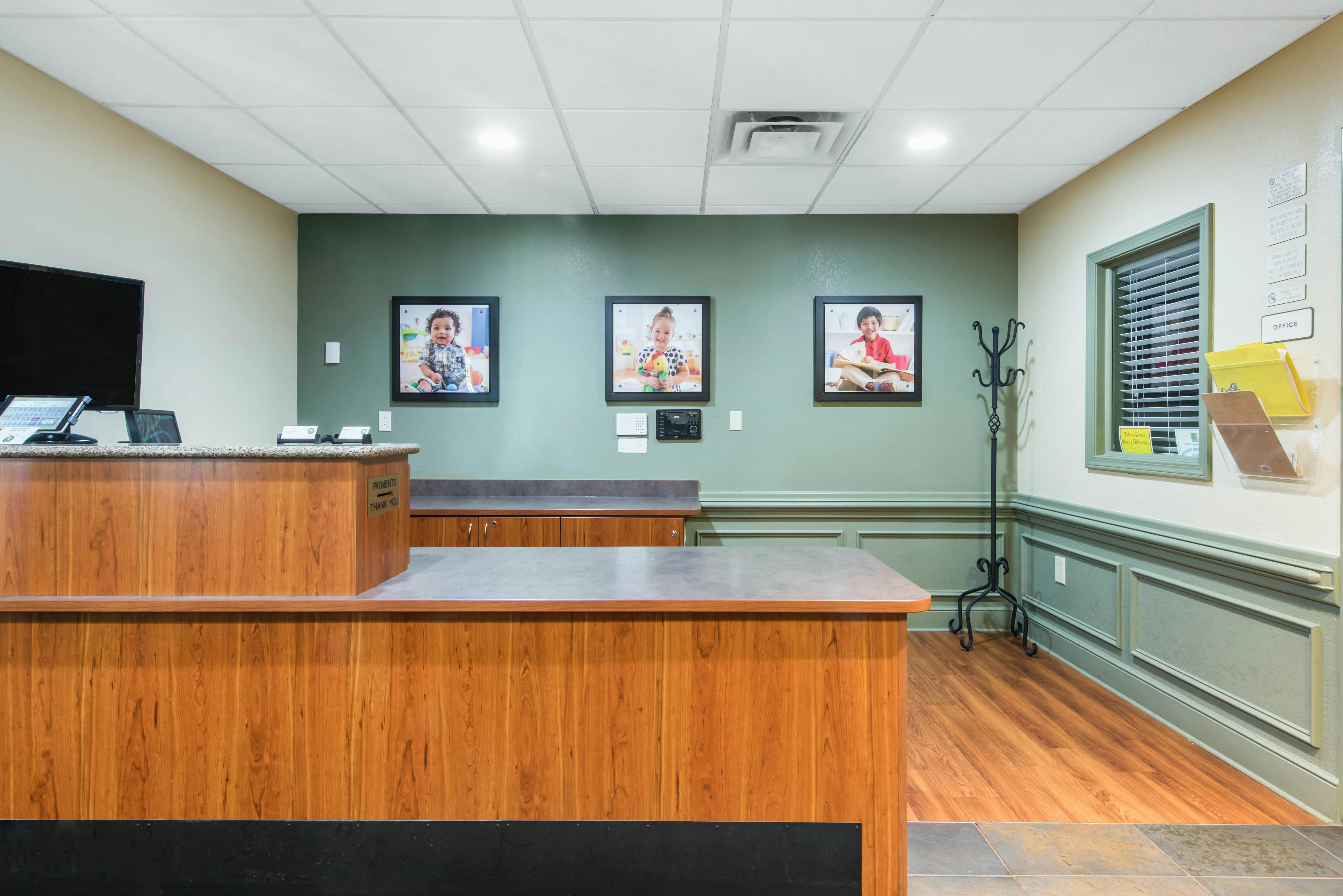 Reception desk with three framed photos of children on the wall behind it