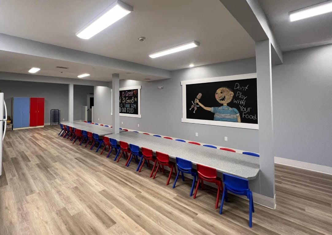 Long tables with red and blue chairs in a room with chalkboards