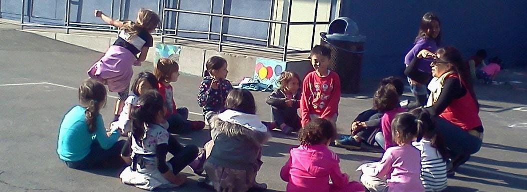 Children and an adult sitting in a circle outdoors