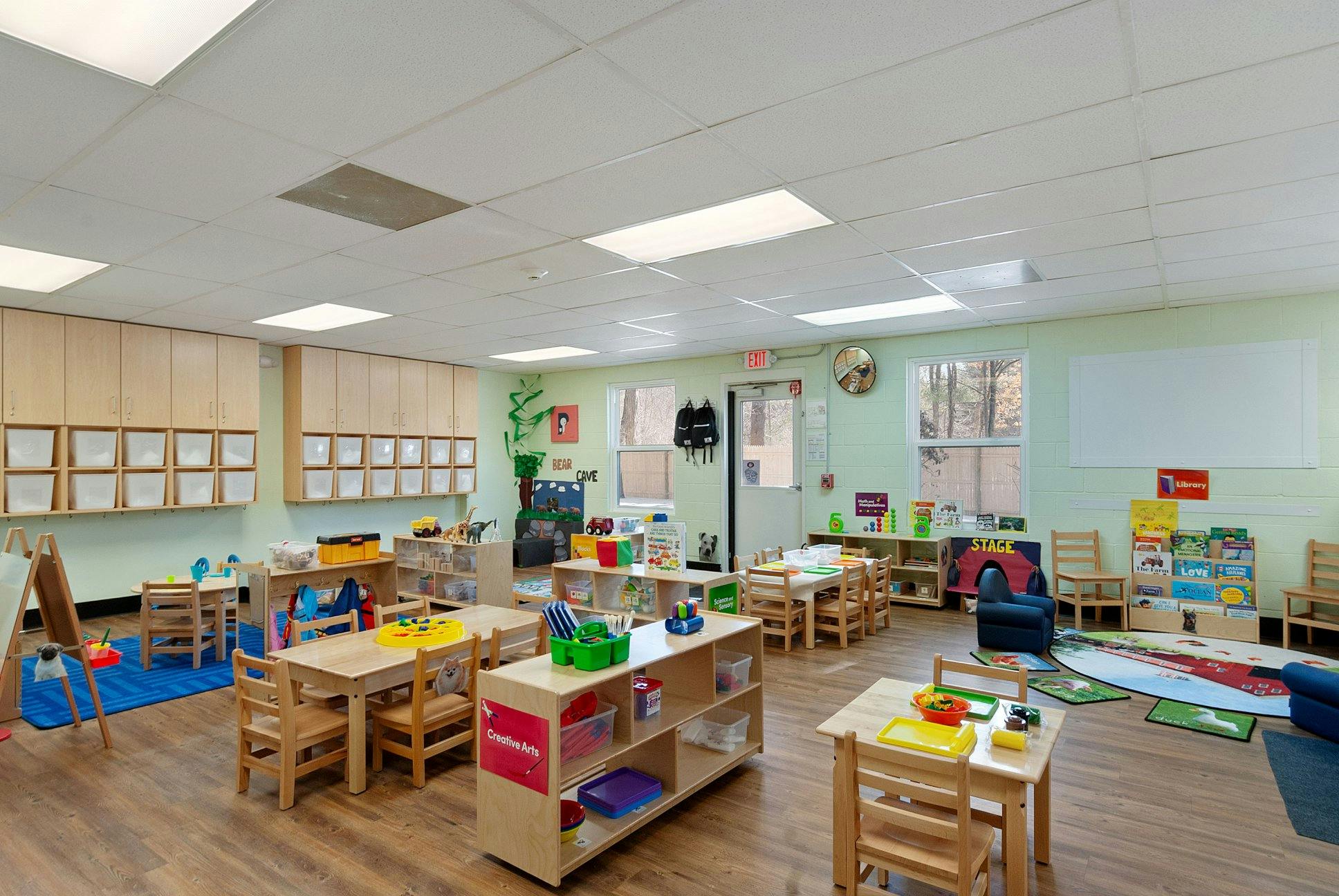 Classroom with multiple tables and chairs, storage, and windows