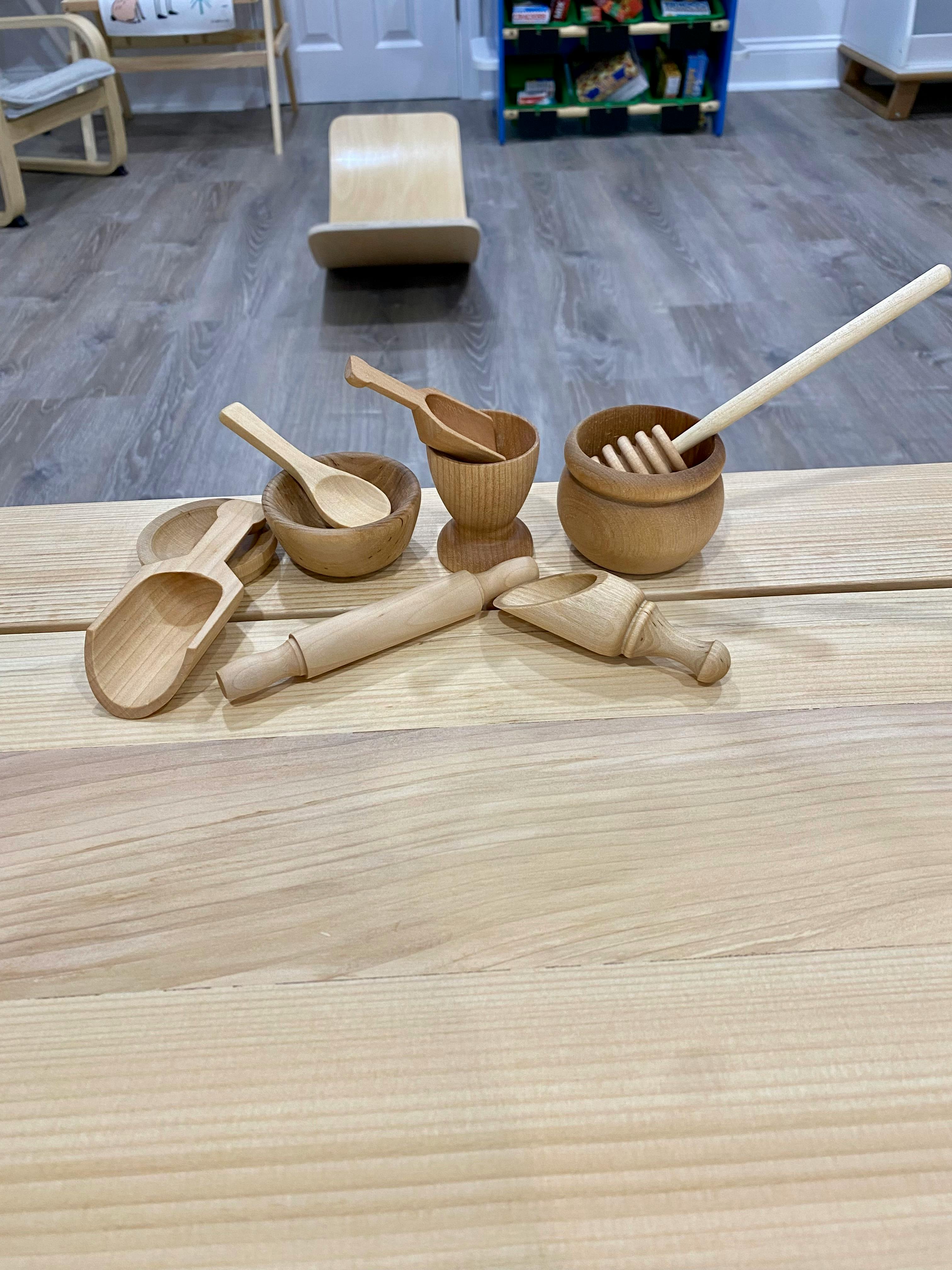 Wooden kitchen utensils including bowls, spoons, a honey dipper, and a rolling pin