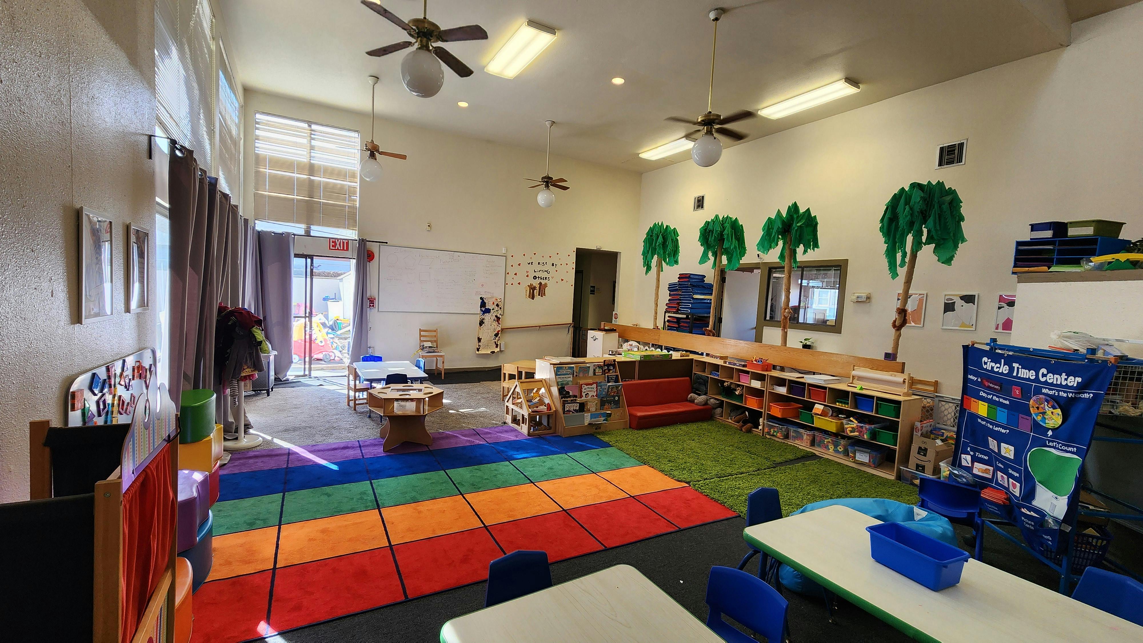 Colorful classroom with tables, chairs, shelving, and rugs
