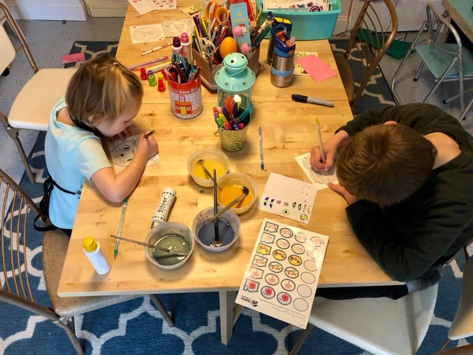 Two children drawing and painting at a table