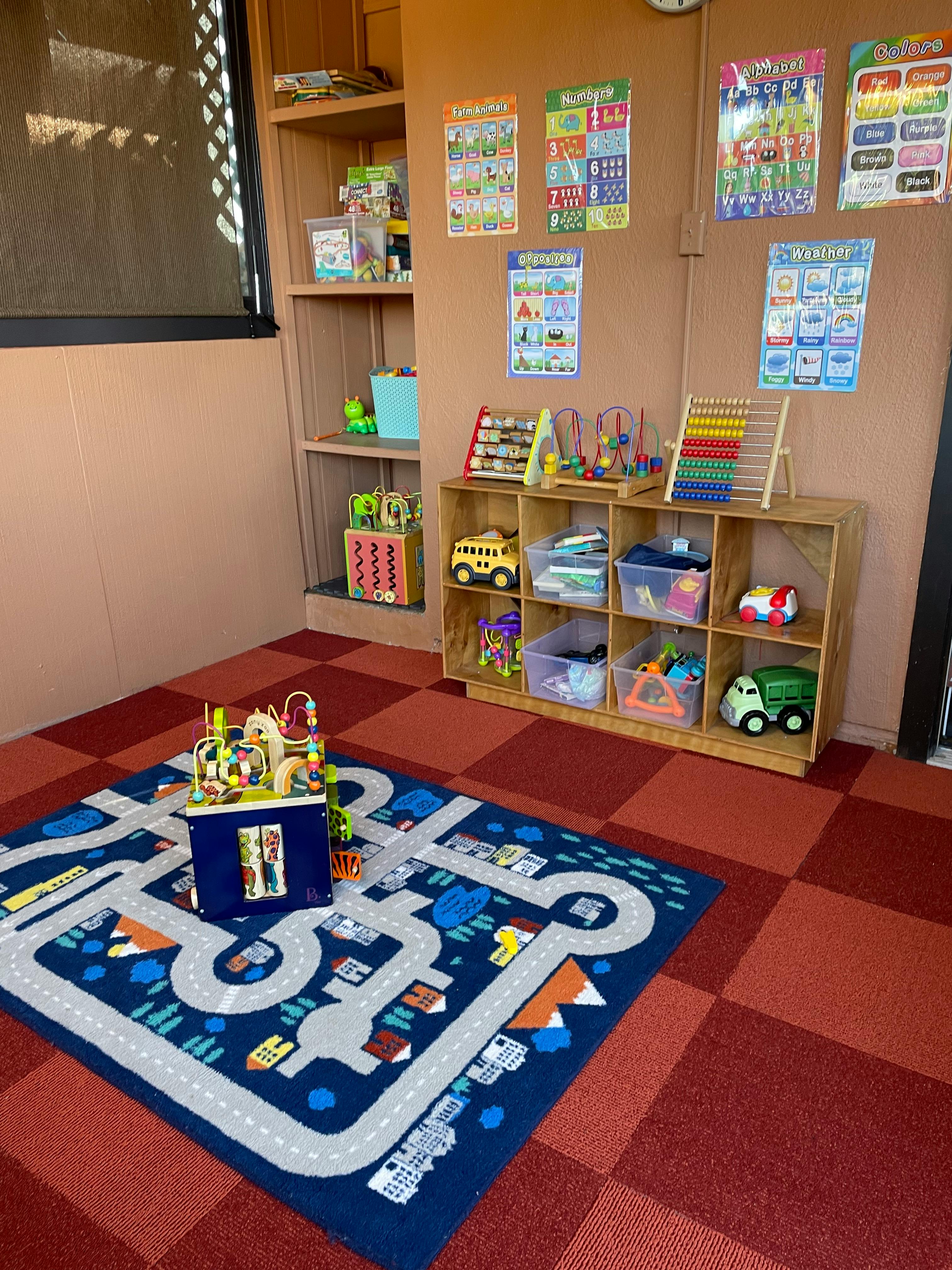 Playroom with a road map rug, shelves of toys, and educational posters