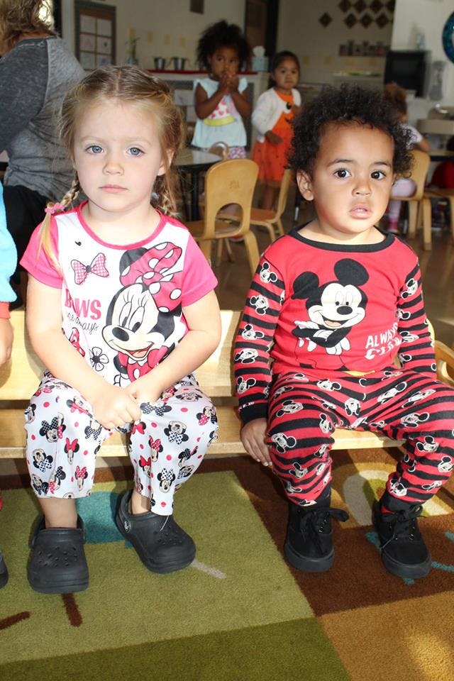 Two children sitting on a bench in a classroom