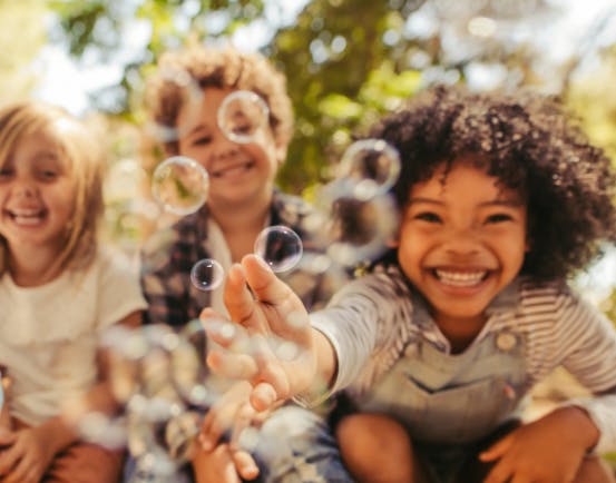 Three children playing with bubbles outdoors