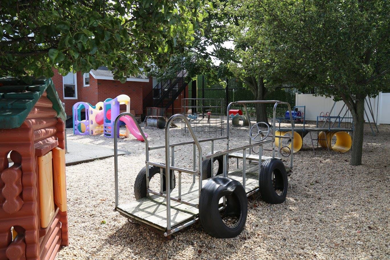 Playground with a metal wagon, playhouse, and colorful climbing structure