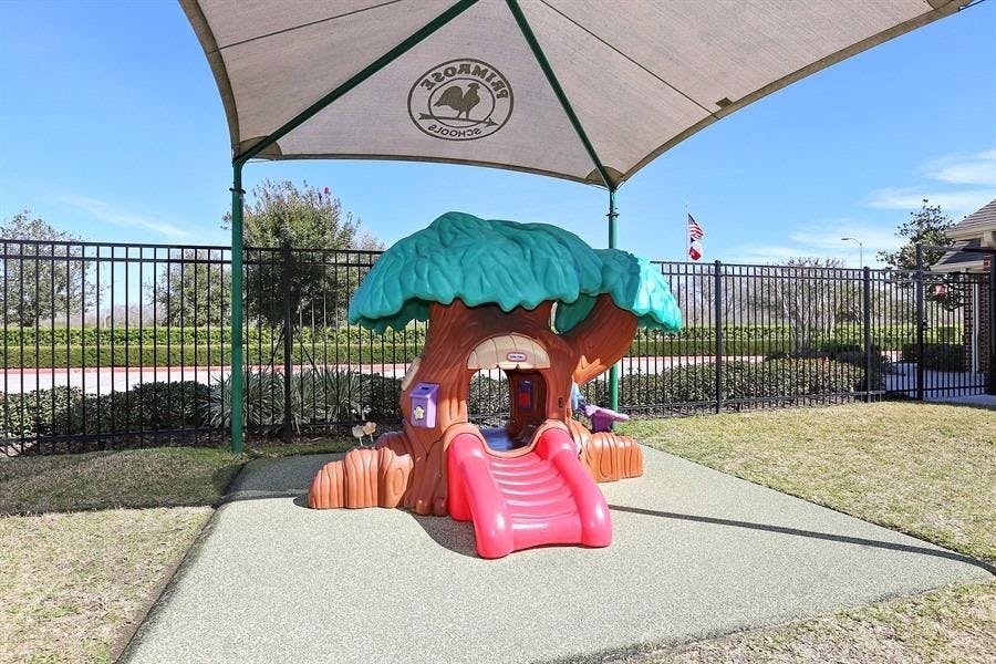 Playground with a tree-shaped play structure and a red slide under a canopy