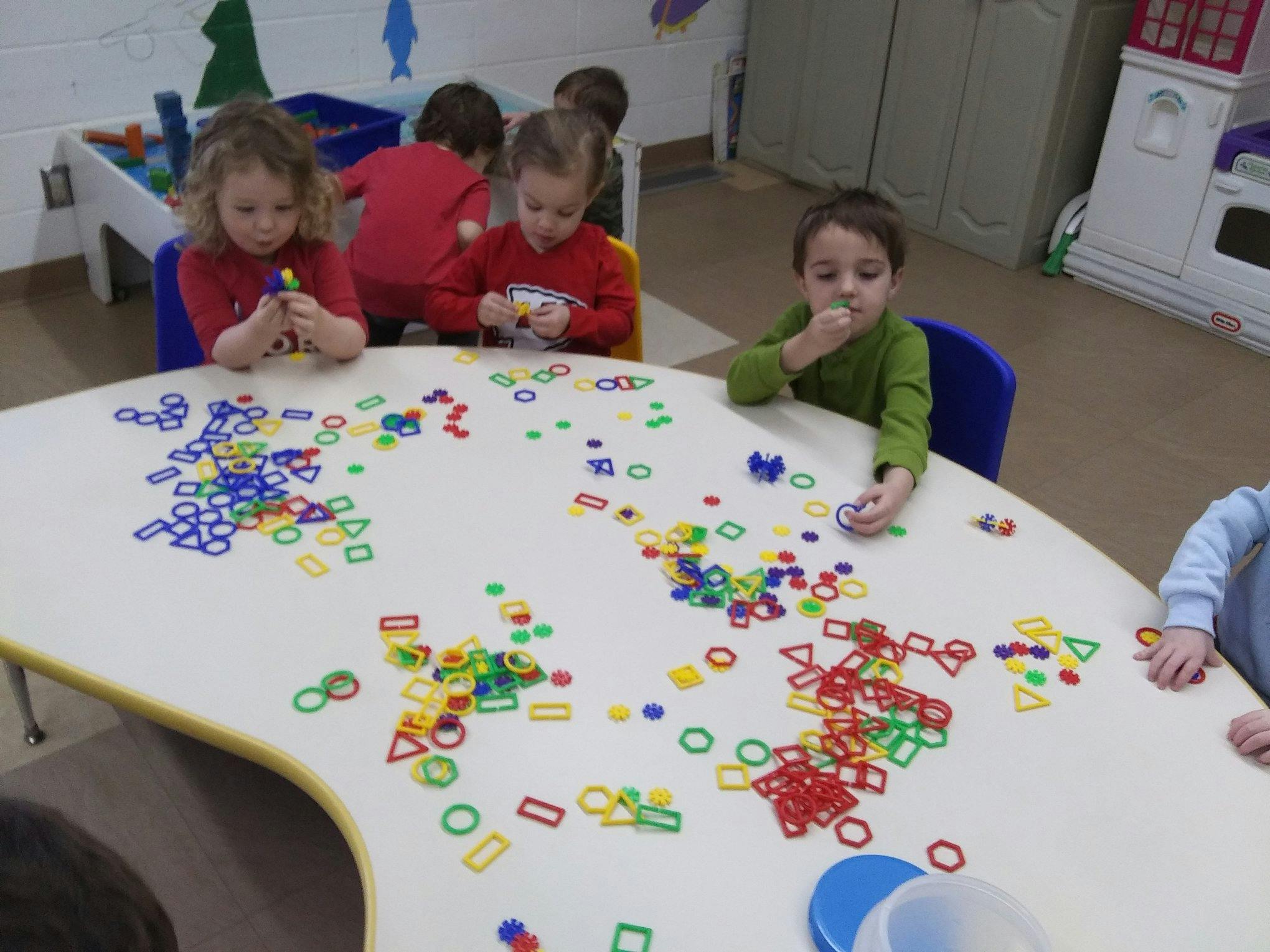 Children playing with colorful shape manipulatives at a table