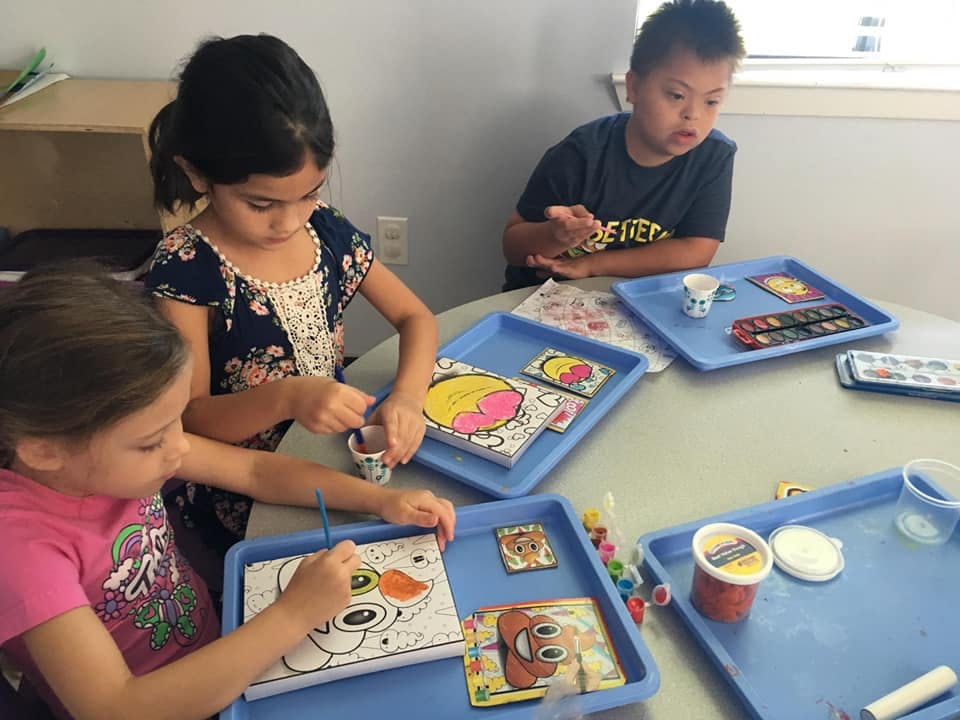 Three children painting and coloring at a table