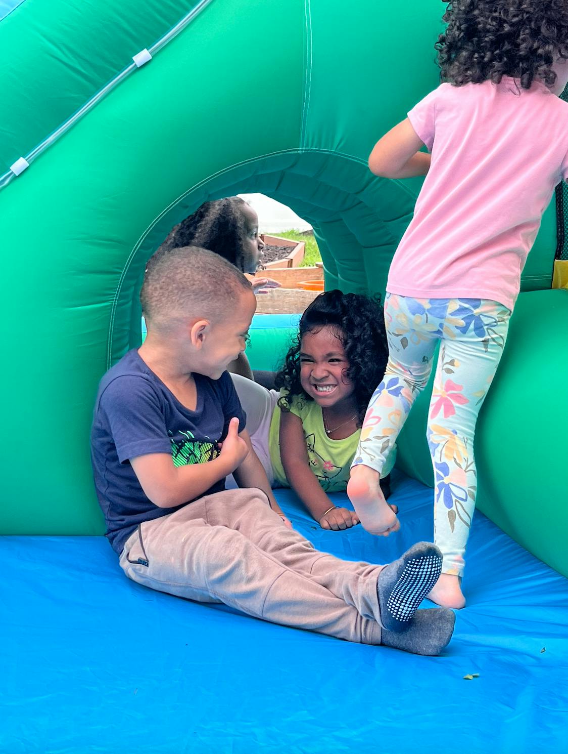 Children playing inside a green inflatable bounce house
