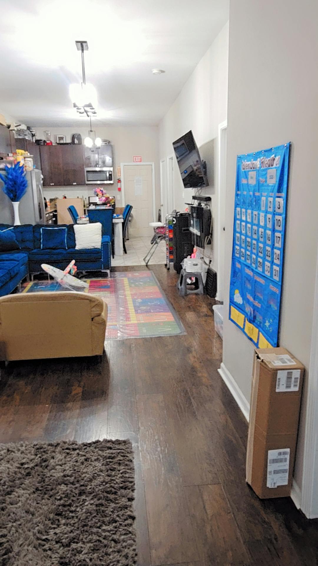 Living room with blue sofa, dining area, and kitchen in the background