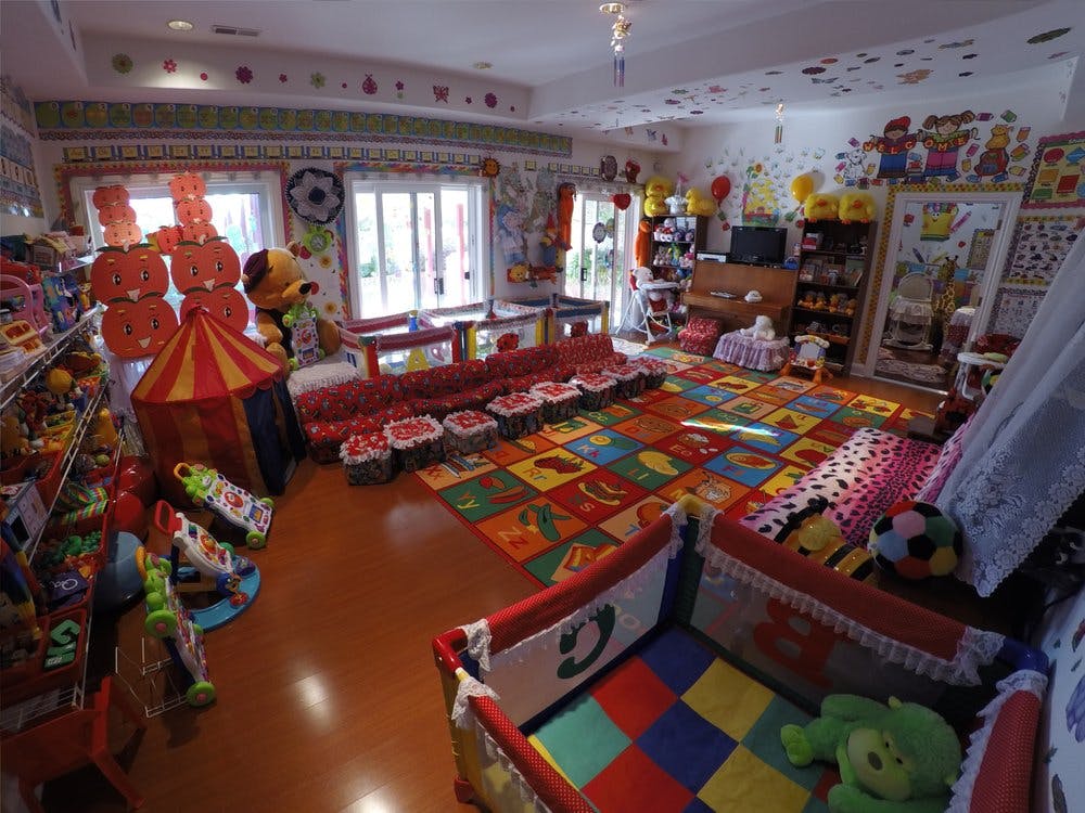 Playroom with colorful rug, toys, and small furniture