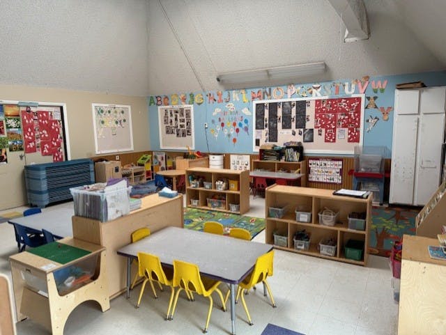 Classroom with child-sized tables and chairs, shelves, and educational decorations