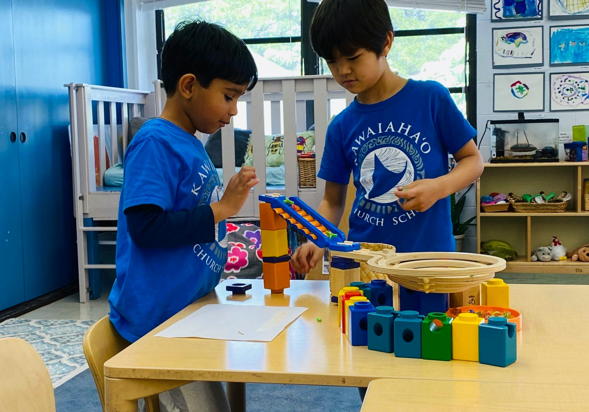 Two children playing with a marble run toy on a table
