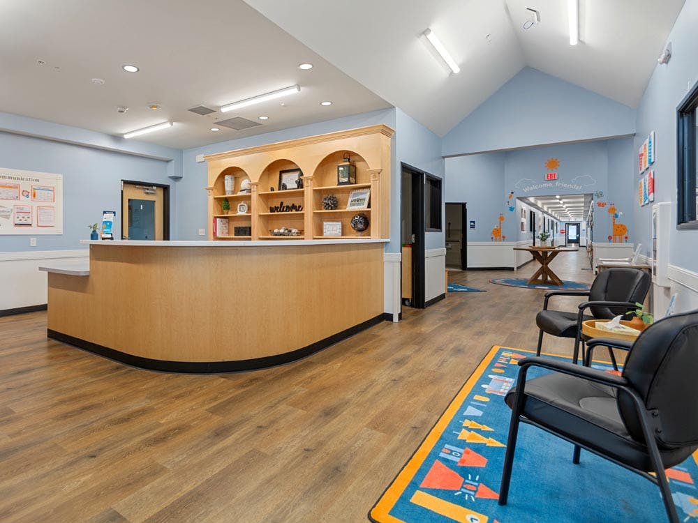 Reception area with a light wood counter, welcome sign, and blue walls