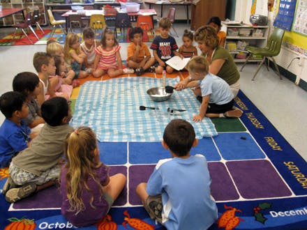 Adult and children sitting on a rug in a classroom
