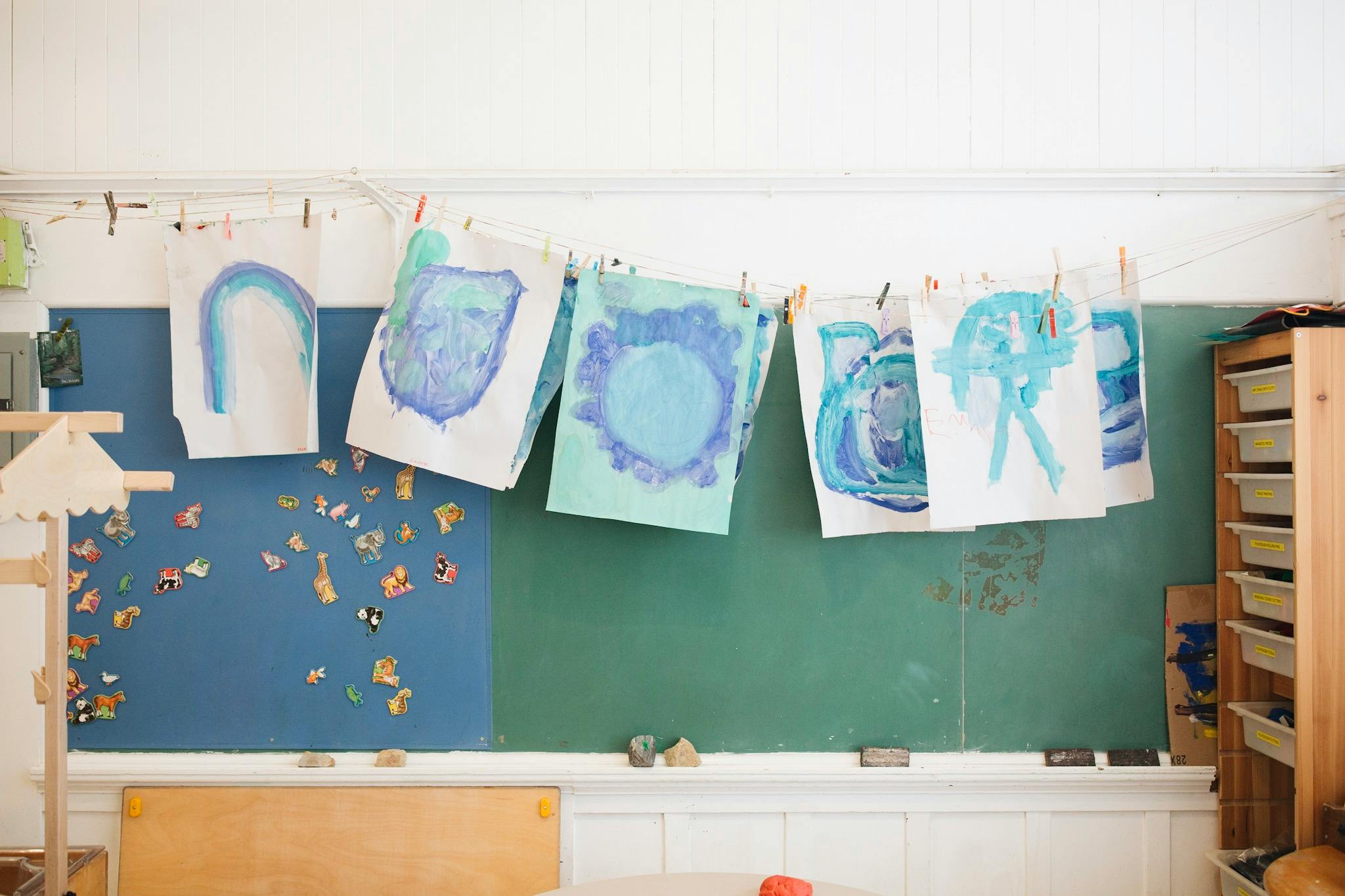 Children's artwork hanging on a line in a classroom