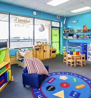 Empty classroom with small tables, chairs, and a colorful rug
