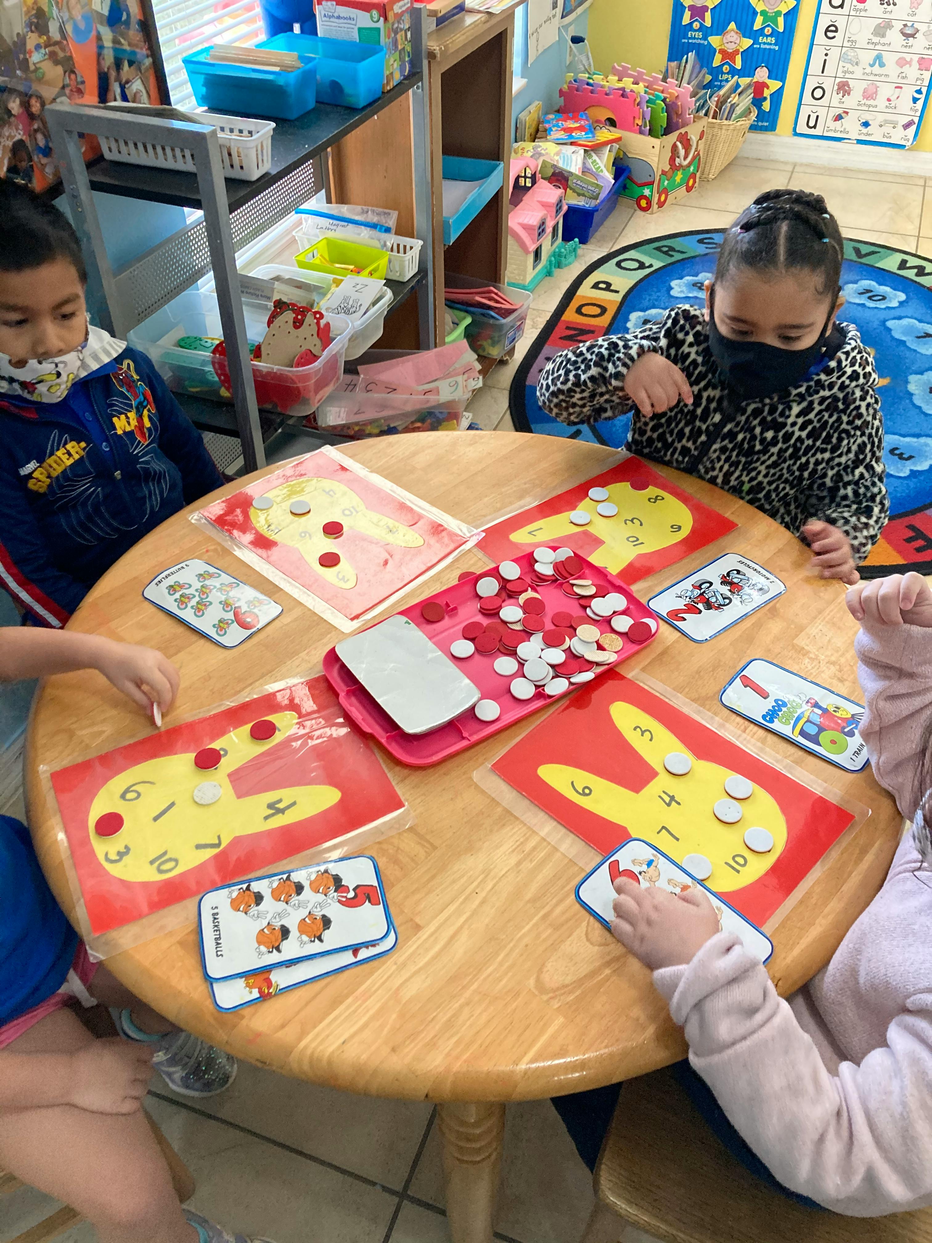 Children at a table playing with number cards and small tokens
