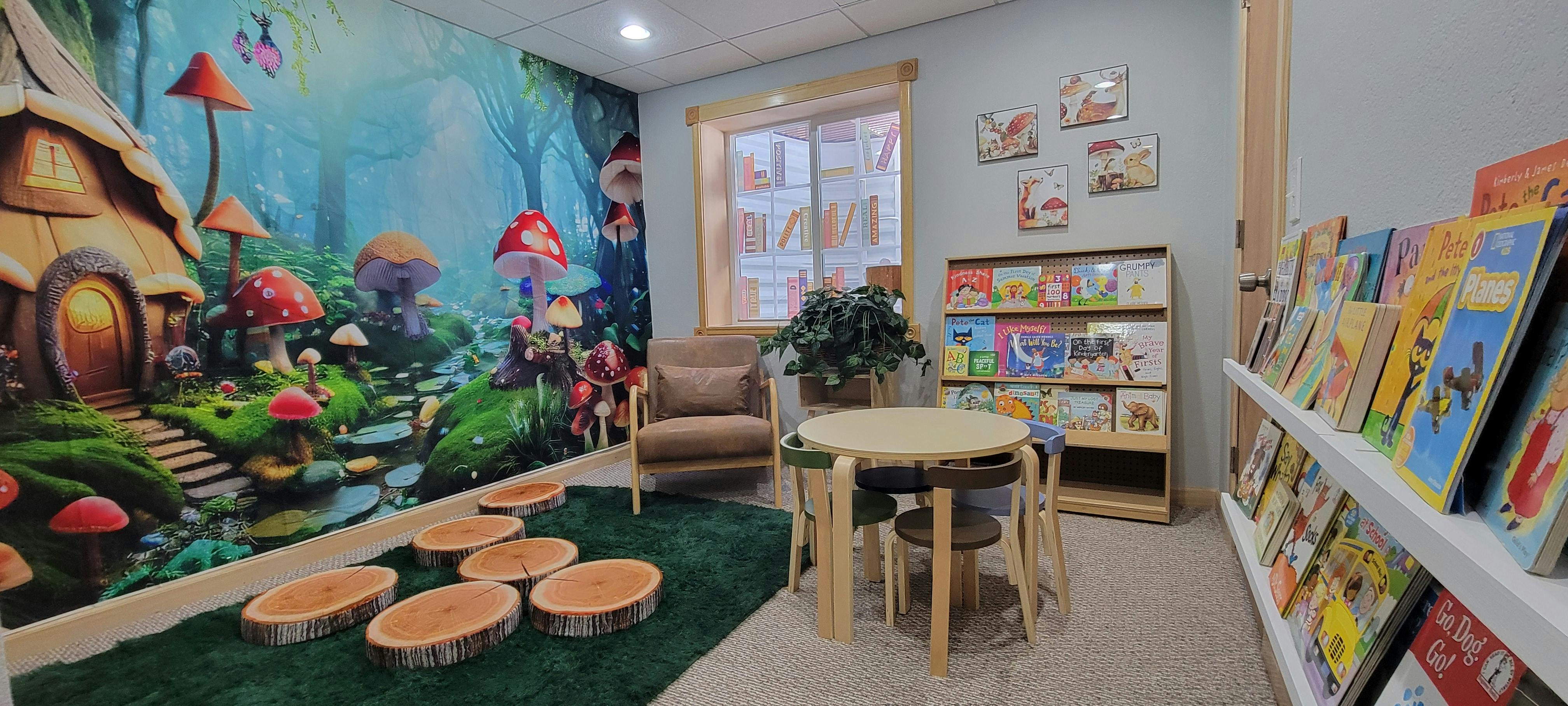 Children's room with a nature mural, small table and chairs, and bookshelves
