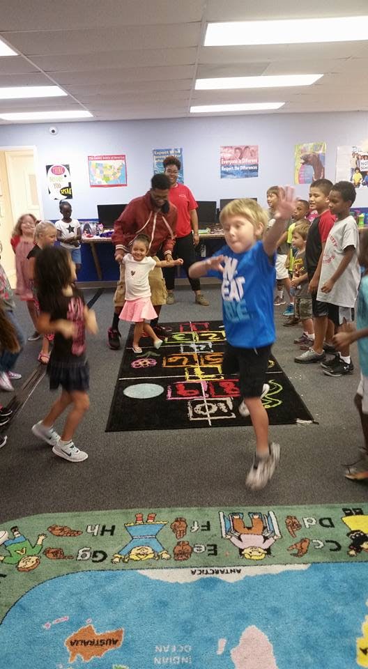 Children and adults playing hopscotch in a classroom