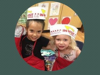 Two children wearing paper hats and aprons