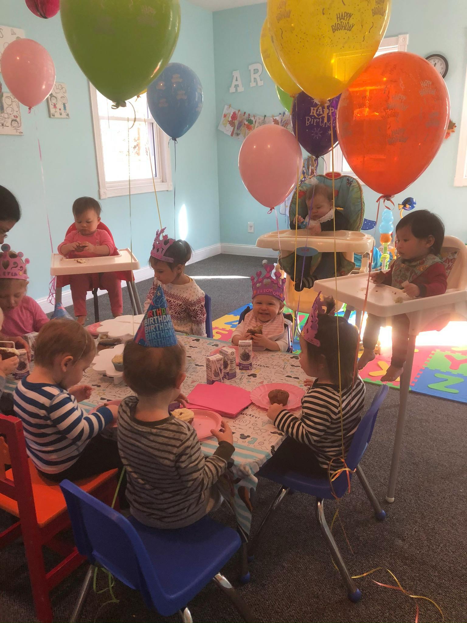 Children sitting at tables with balloons overhead