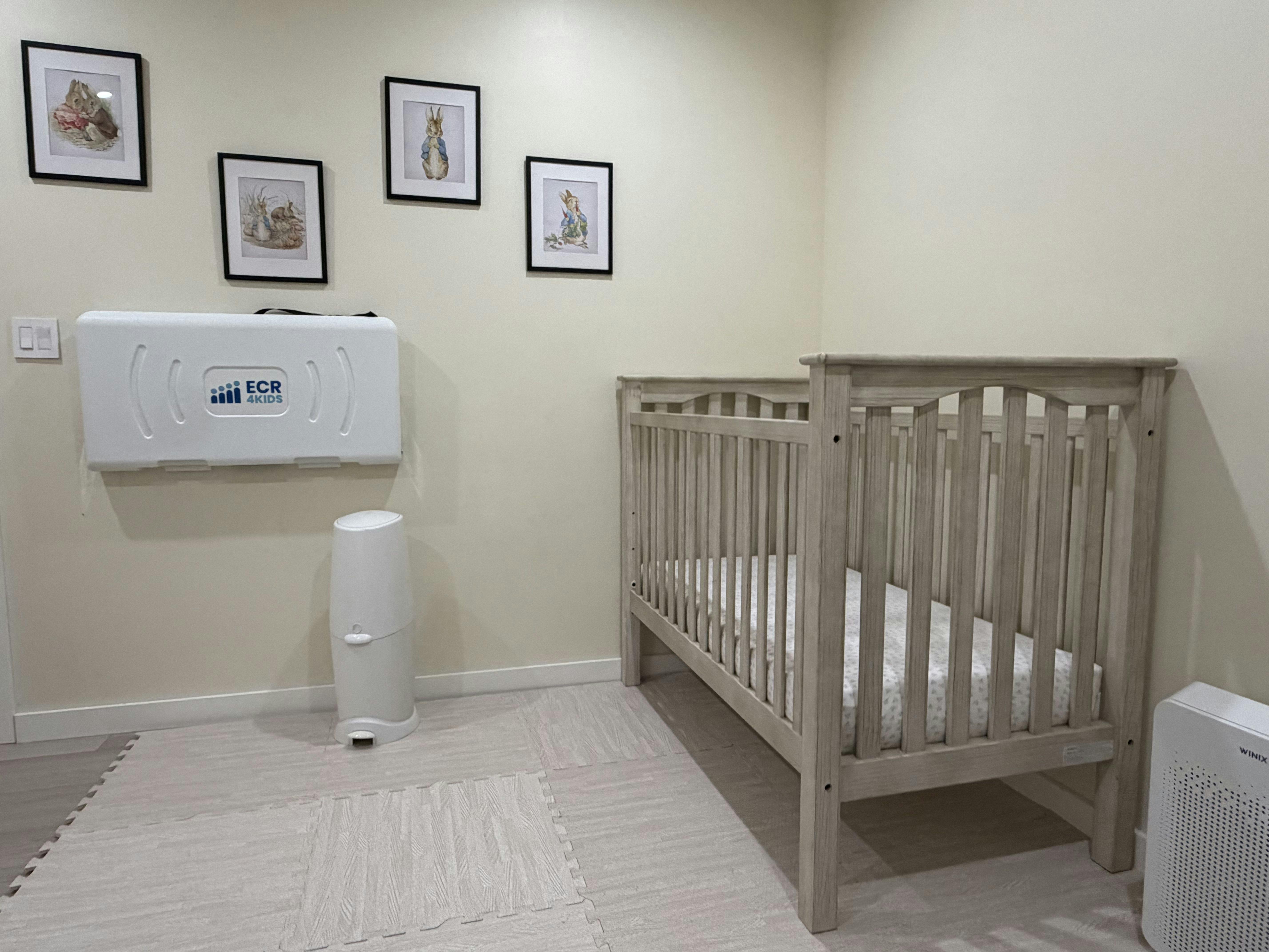 Baby changing station, crib, and framed art in a nursery