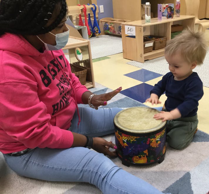 Person in mask and child playing a drum