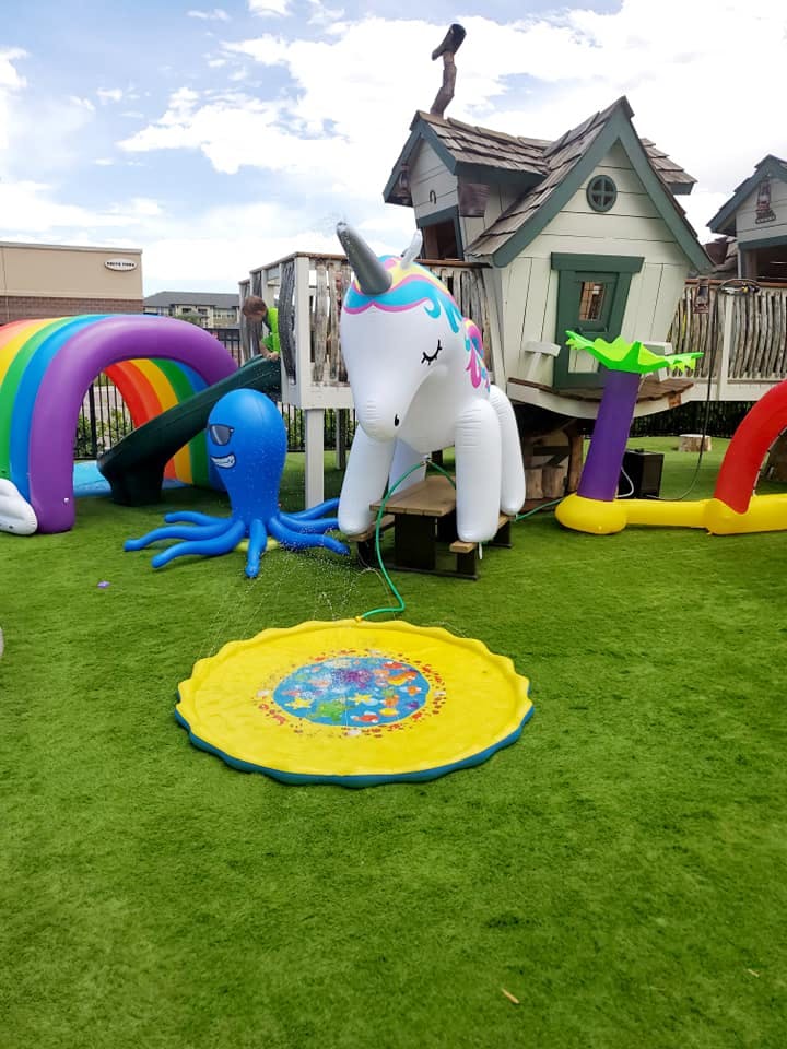 Inflatable unicorn, octopus, and rainbow arch on green turf