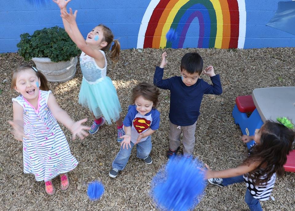 Children playing outdoors with blue pom-poms