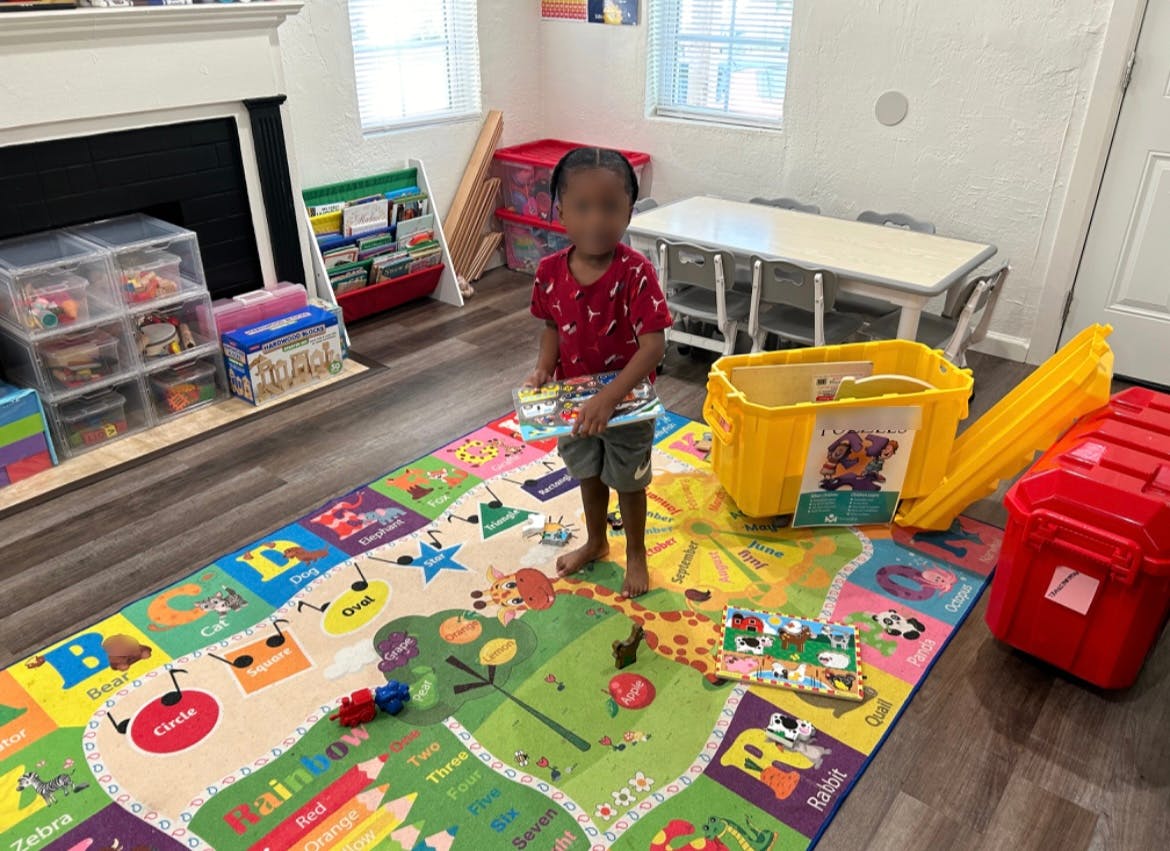 Child standing on a colorful playmat in a room with toys