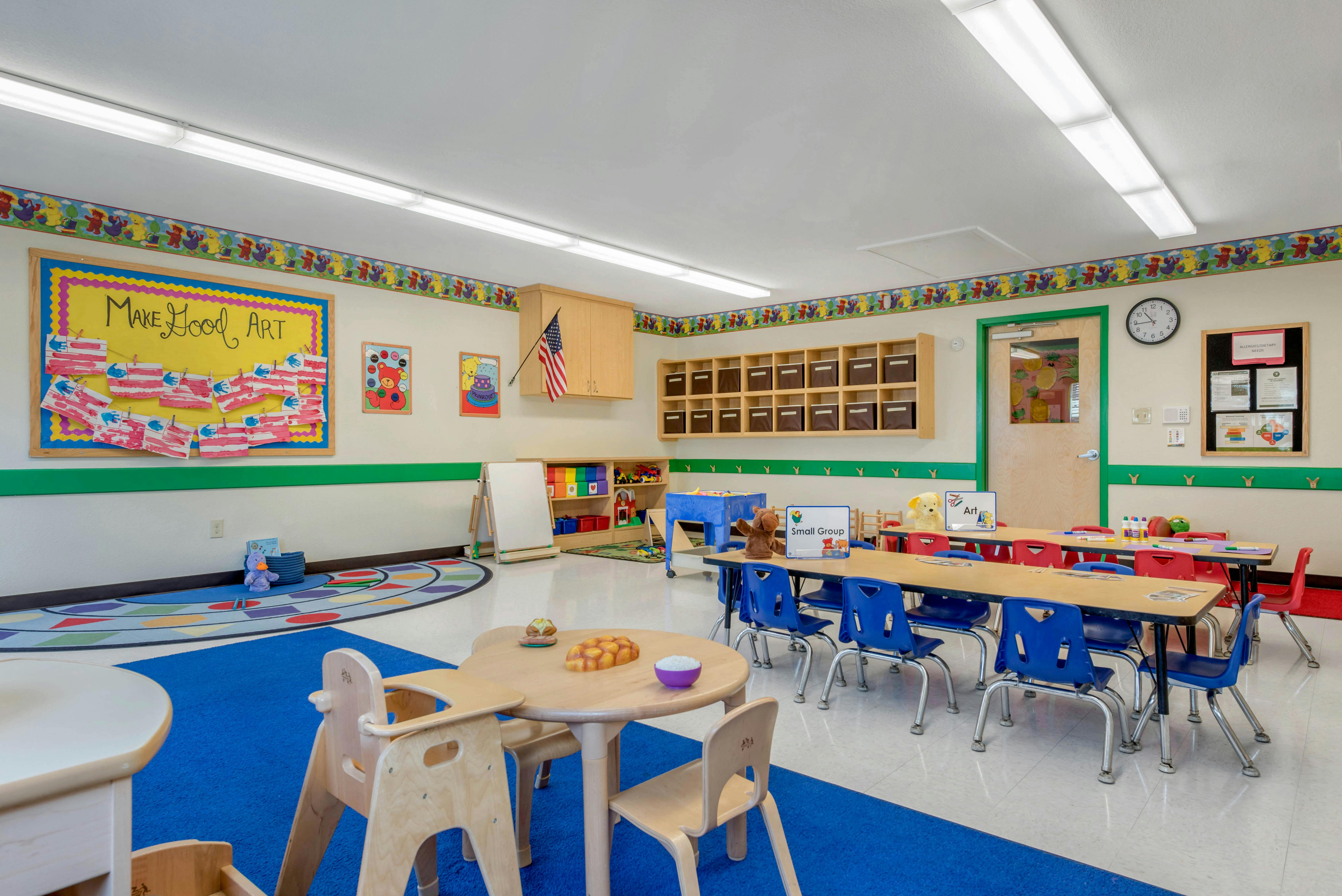 An empty early childhood classroom with multiple tables and chairs