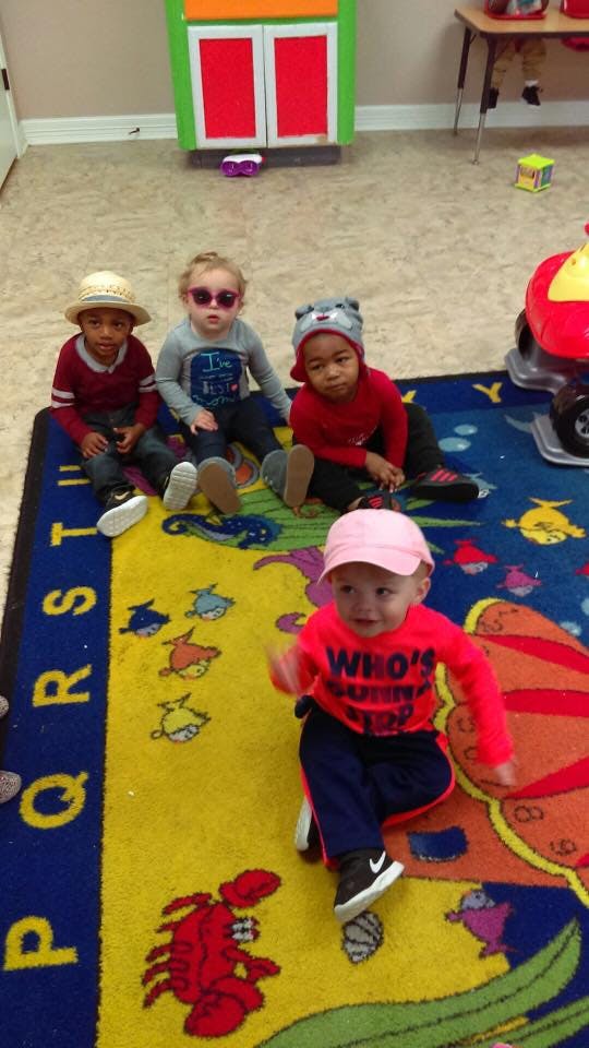 Four children sitting on a colorful rug