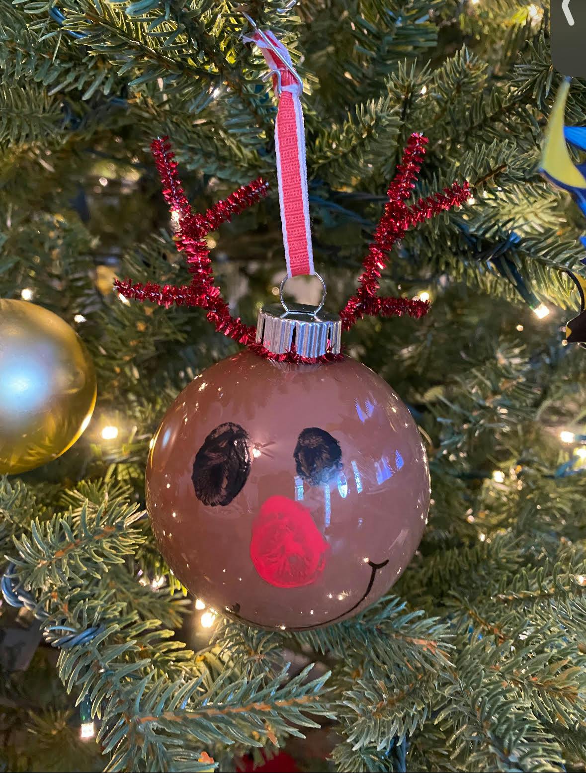 Reindeer ornament with red pipe cleaner antlers on a Christmas tree