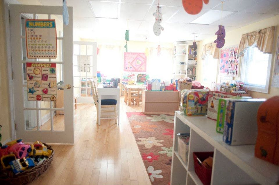 Classroom with tables, chairs, and shelves of books and toys
