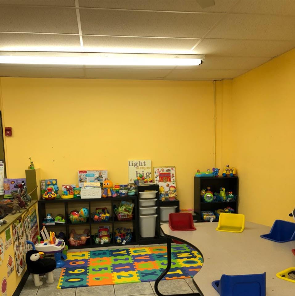 Playroom with shelves of toys, colorful floor mat, and small chairs