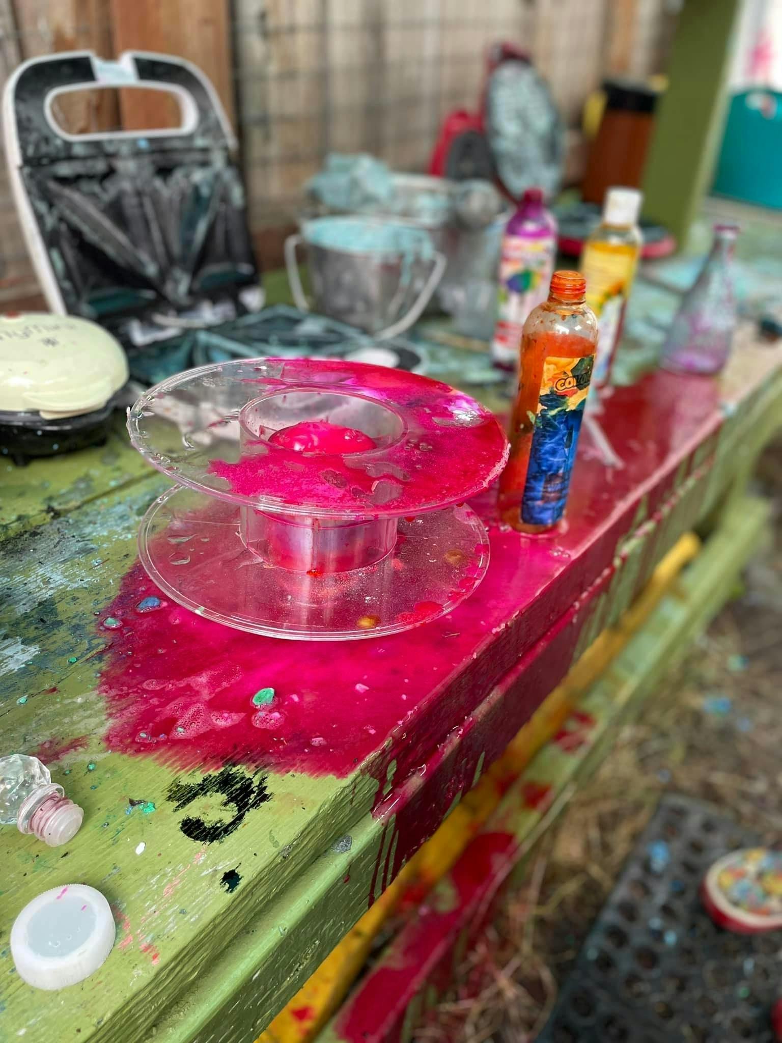 Pink liquid spilled on a green and red surface with bottles and a waffle maker