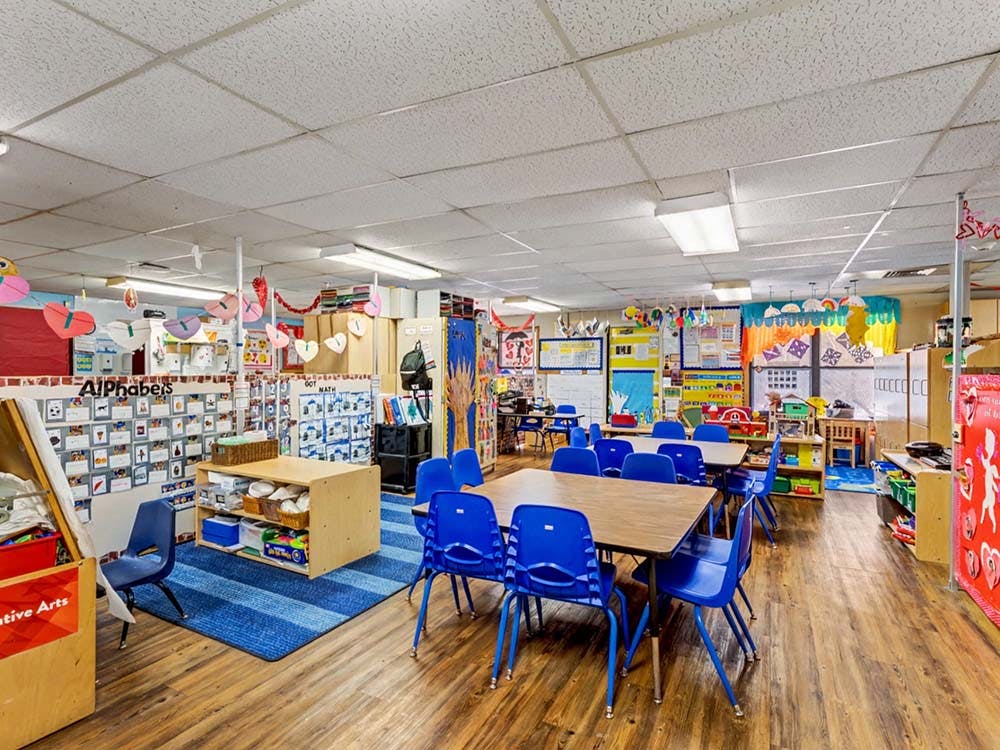 Empty classroom with small tables, blue chairs, and colorful decorations