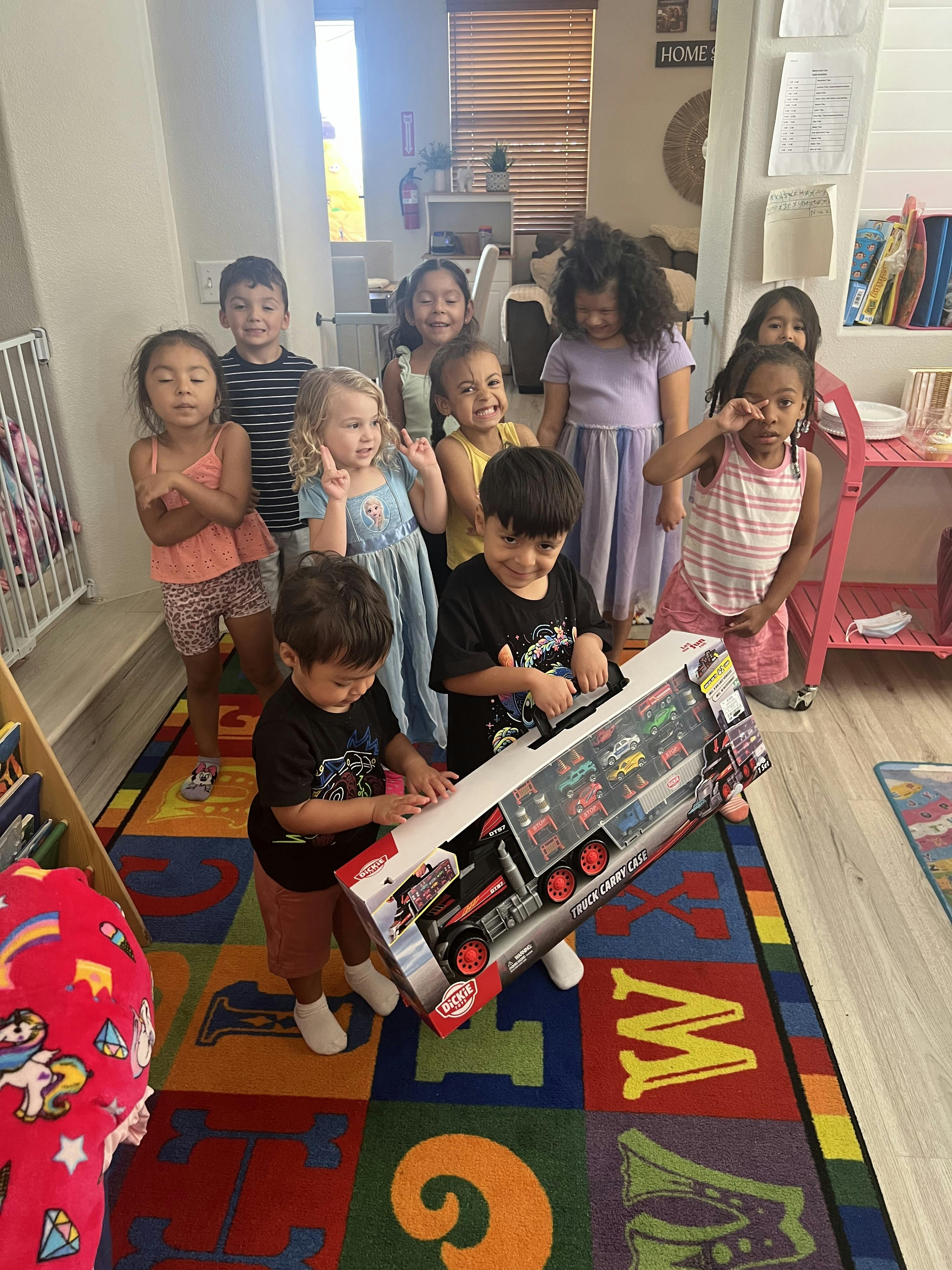 Children gathered around a child opening a toy truck carry case