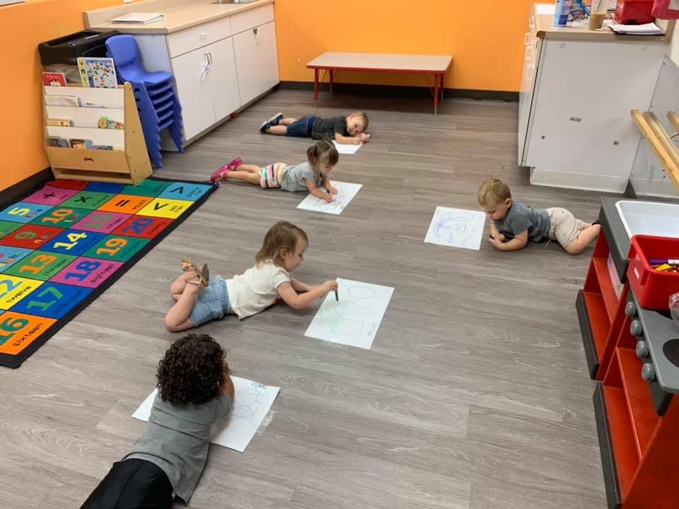 Children lying on the floor drawing on paper