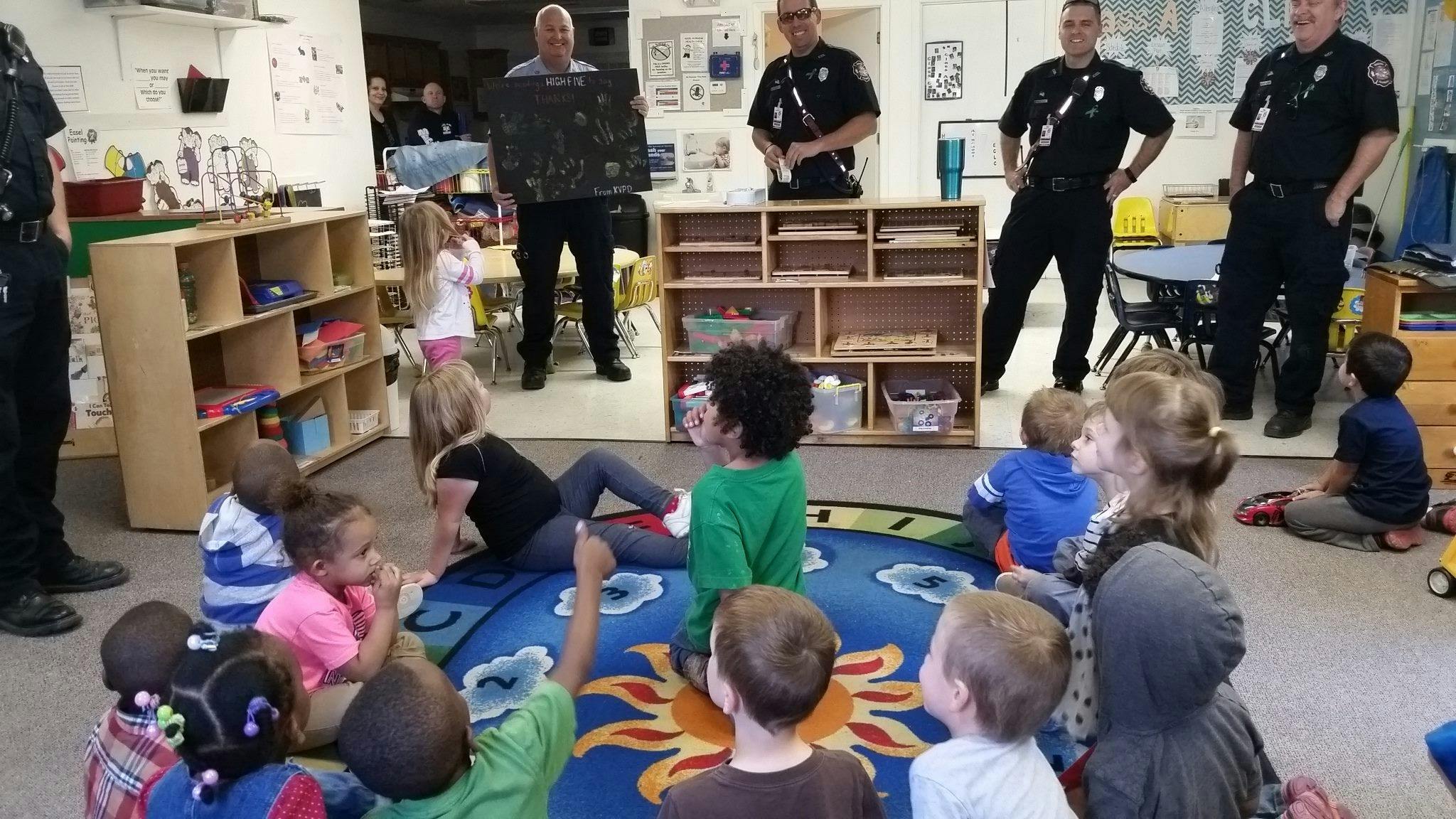 Adults in uniform with children in a classroom