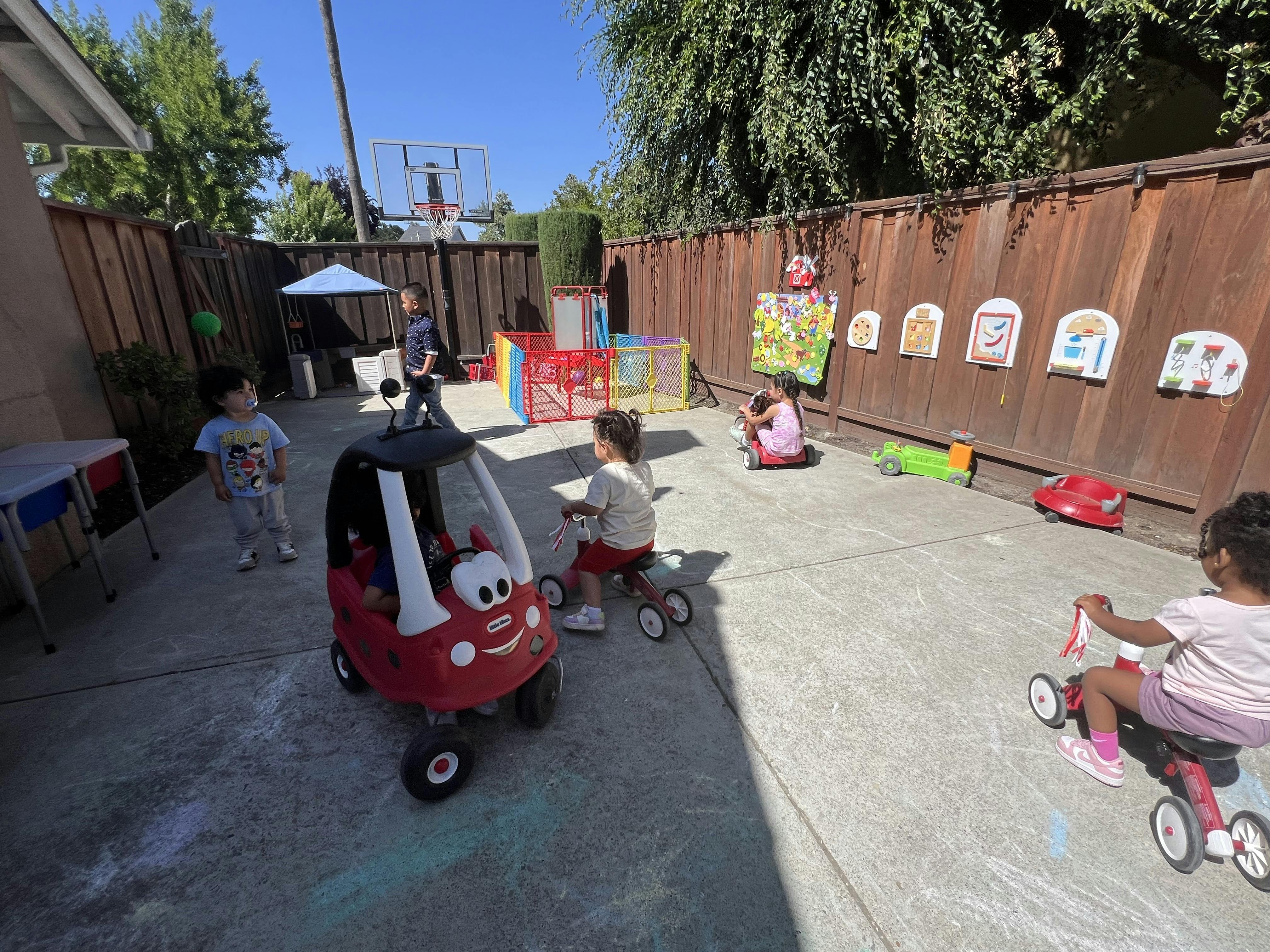 Children playing with ride-on toys in a paved outdoor area