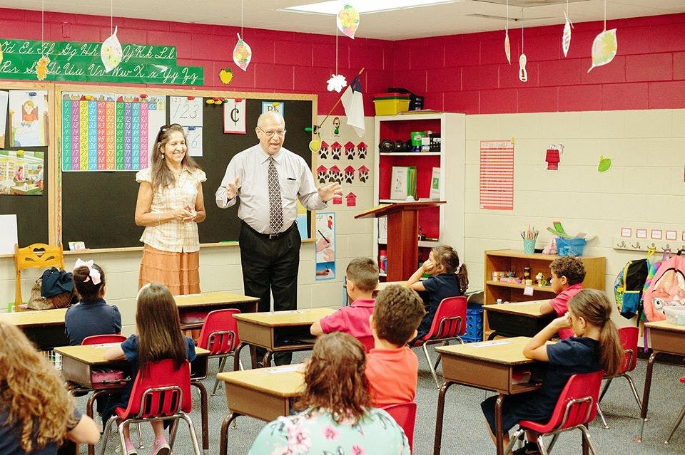 Two adults speaking to children in a classroom