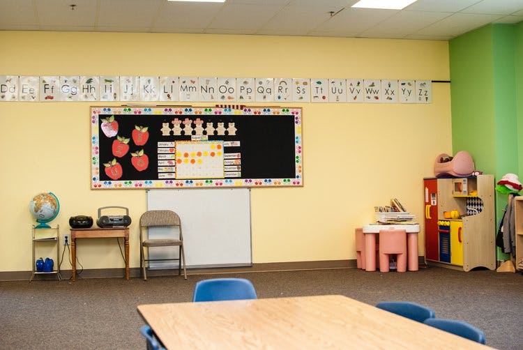 Empty classroom with a bulletin board, whiteboard, and small furniture