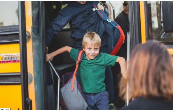 Child with backpack exiting a school bus