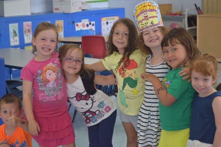 Group of children posing together in a classroom