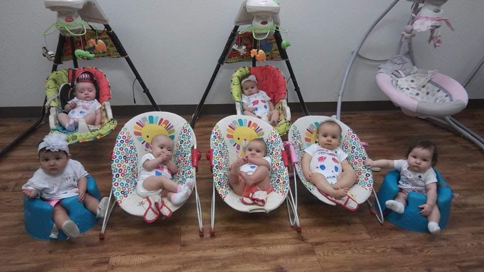 Multiple babies sitting in various infant seats and bouncers